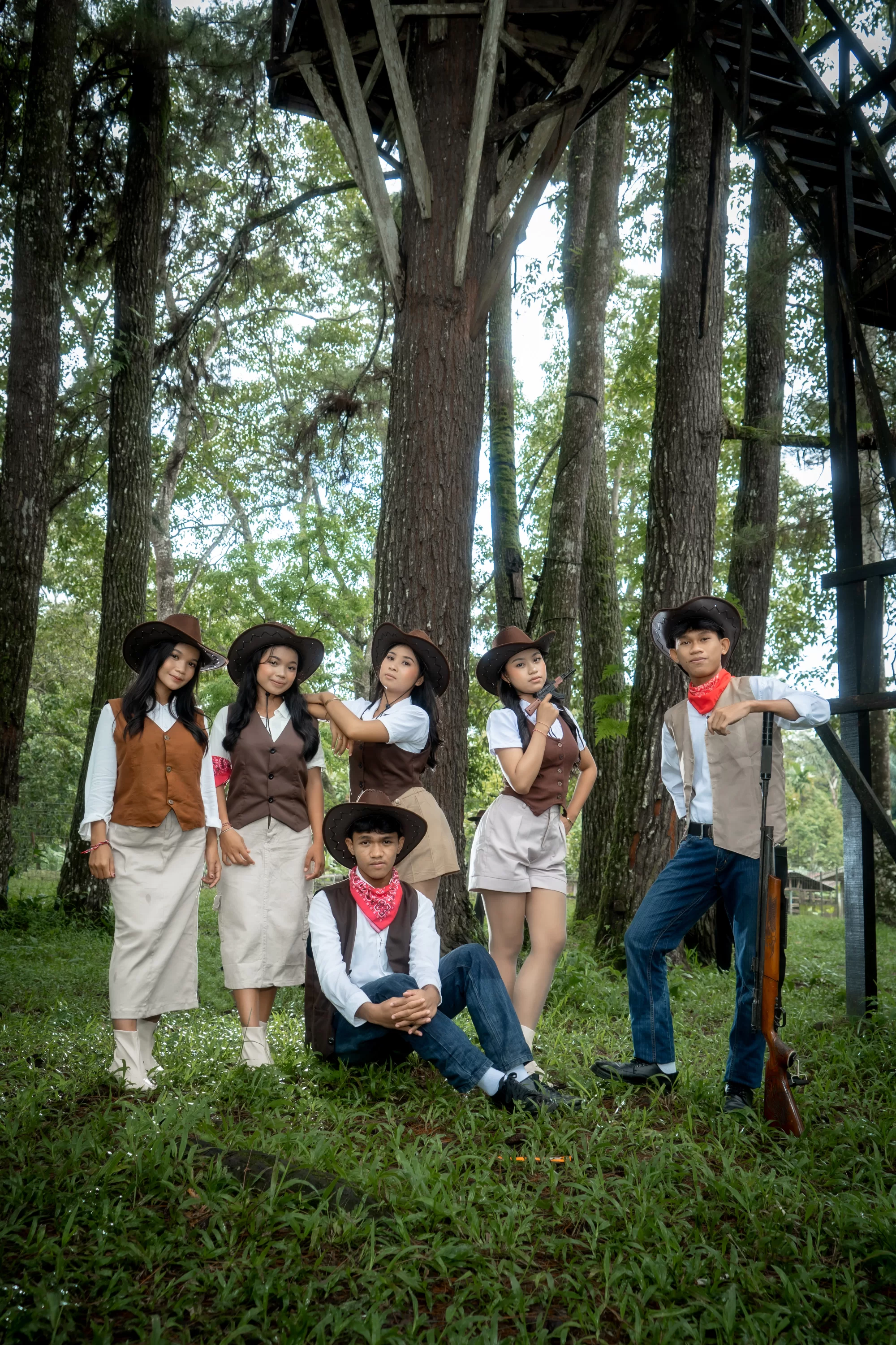 Sekelompok siswa berpose mengenakan topi koboi dan jaket kulit bergaya western di padang rumput terbuka