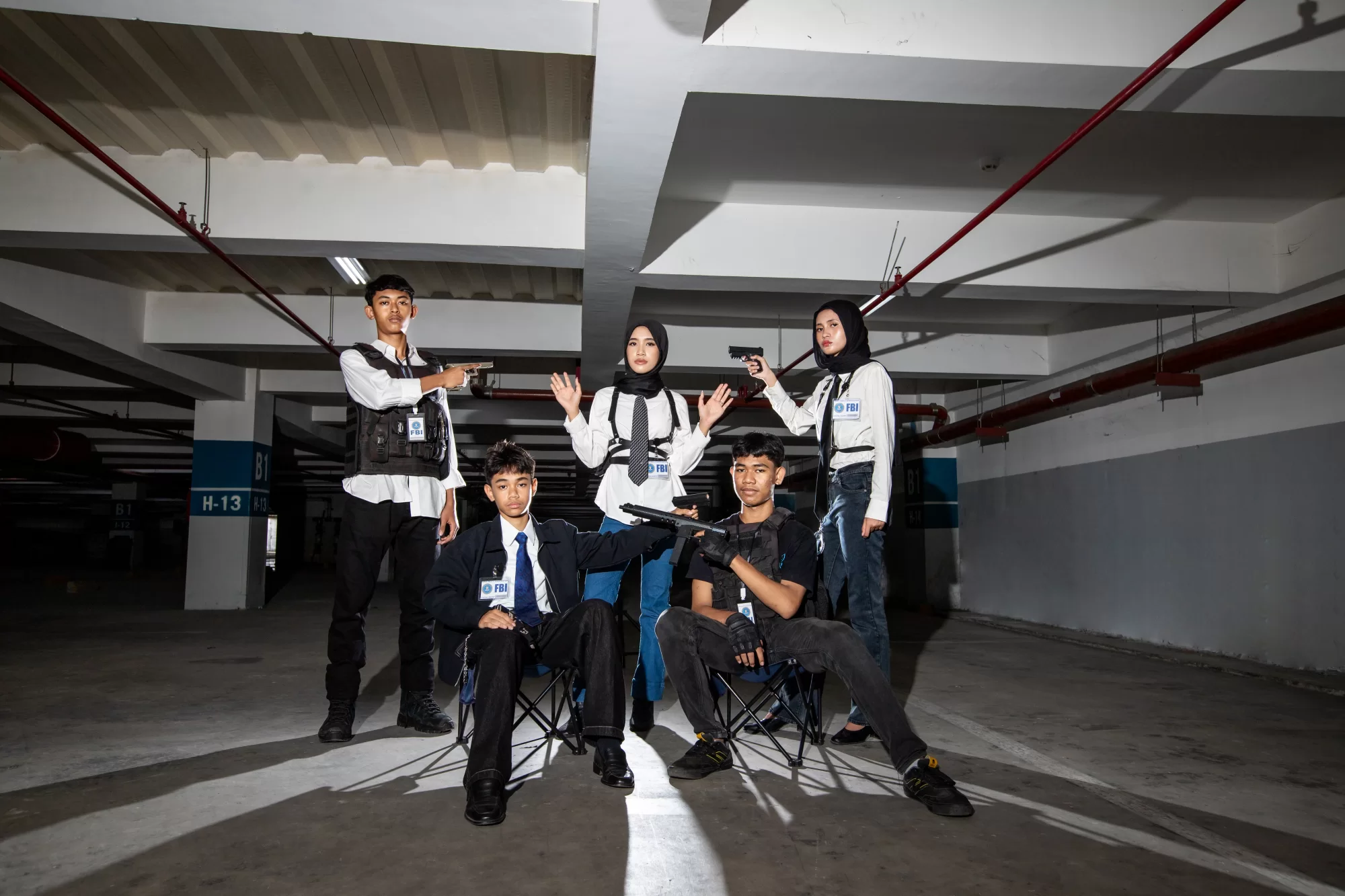 Potret tegang dan penuh siaga para siswa berpose membawa properti pistol mainan bergaya agen rahasia dengan pencahayaan dramatis